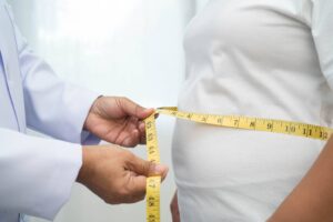 A doctor measuring the waist of a woman.
